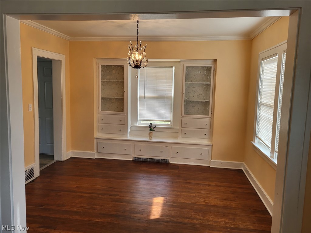 955 Nela View Road Cleveland Heights, OH 44112 - Photo 4 of 34 Empty room featuring an inviting chandelier, dark hardwood / wood-style floors, a wealth of natural light, and crown molding