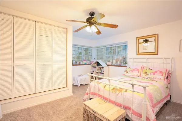 a bedroom with a bed a large window and a flat tv screen on a dresser