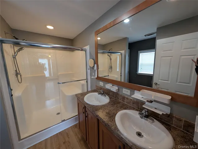 a bathroom with a granite countertop sink a mirror and a shower
