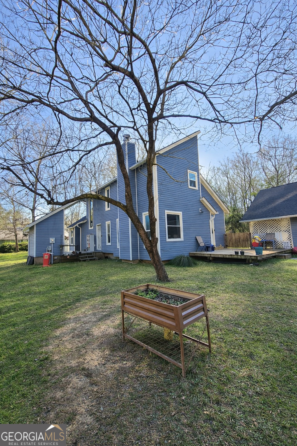 a brick house with a big yard plants and large trees