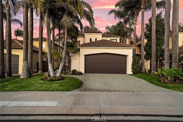 front view of a house with a yard and palm trees