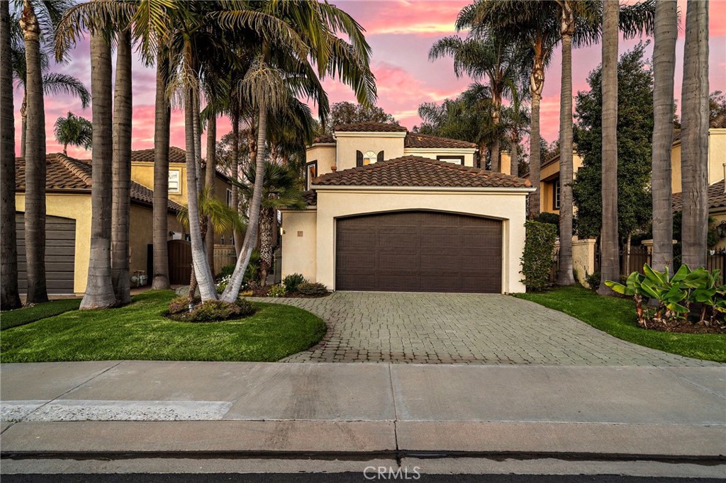 front view of a house with a yard and palm trees