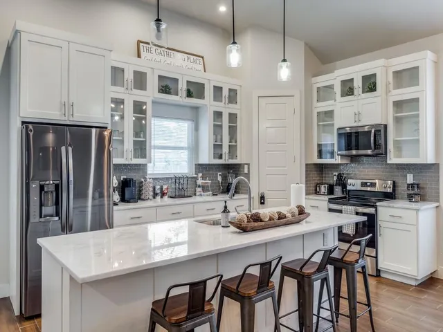 a kitchen with stainless steel appliances granite countertop a sink a stove a refrigerator a microwave oven with cabinets and wooden floor