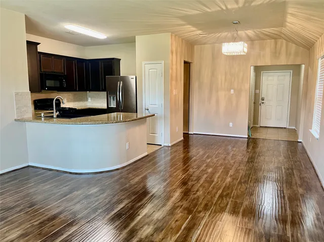 a view of kitchen with stainless steel appliances wooden floor and cabinets