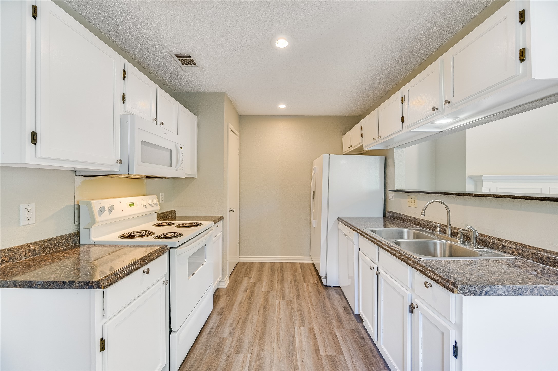 526 Cutty Trail, Unit B Lakeway, TX 78734 - Photo 6 of 10 Galley kitchen featuring white cabinetry, gray speckled countertops, wood-finish flooring, a double basin stainless steel sink, and a white electric range