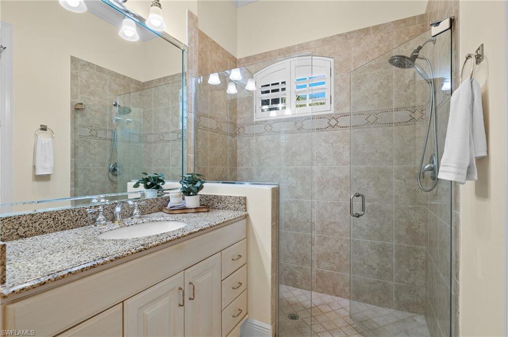 17046 Porta Vecchio Way, Unit 101 Naples, FL 34110 - Photo 12 of 27 a bathroom with a granite countertop sink a mirror and shower