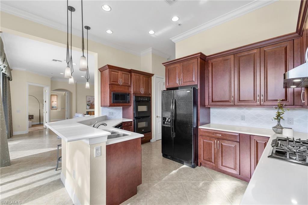 17046 Porta Vecchio Way, Unit 101 Naples, FL 34110 - Photo 6 of 27 a kitchen with stainless steel appliances granite countertop a refrigerator a sink a stove and a wooden cabinets