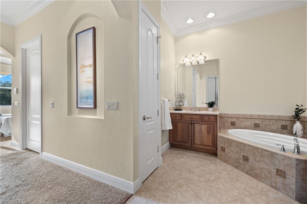 17046 Porta Vecchio Way, Unit 101 Naples, FL 34110 - Photo 10 of 27 a bathroom with a double vanity sink a toilet a mirror and bathtub