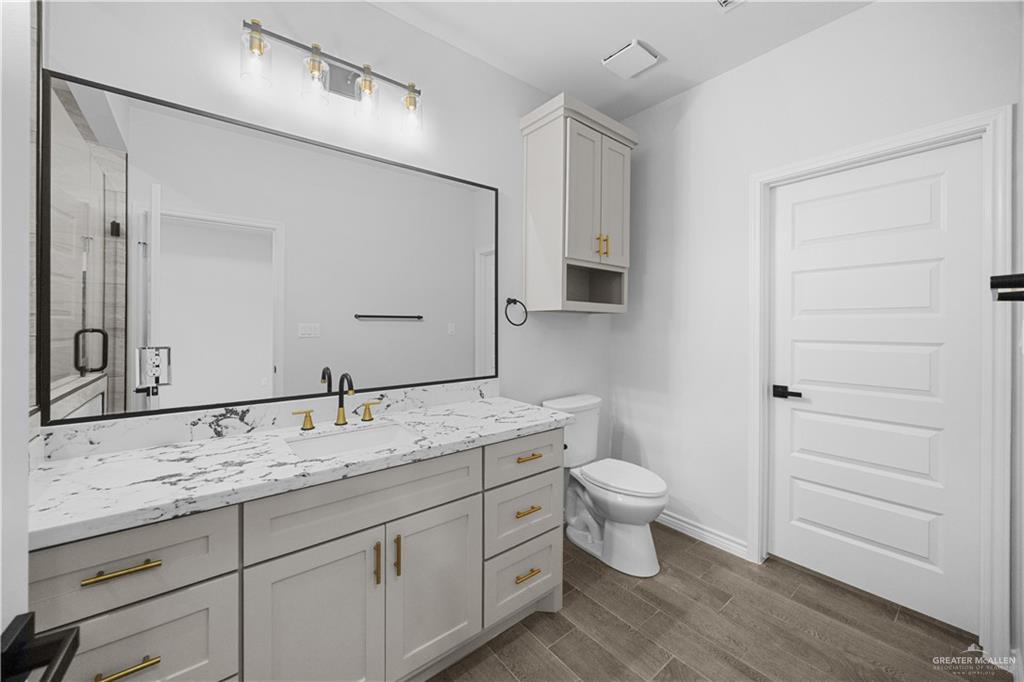 3409 Tyler Street Mission, TX 78572 - Photo 8 of 14 a bathroom with a granite countertop sink toilet and mirror