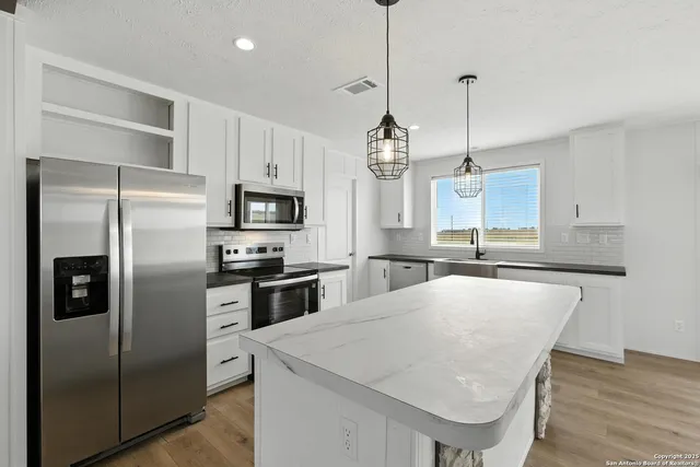 a kitchen with stainless steel appliances granite countertop a refrigerator a sink dishwasher a stove and white cabinets