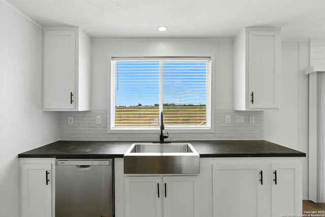 a kitchen with granite countertop white cabinets sink and window