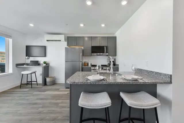 a kitchen with kitchen island granite countertop a sink and a refrigerator