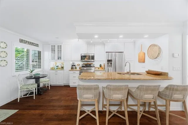 a kitchen with stainless steel appliances granite countertop a table chairs stove a sink dishwasher and cabinets with wooden floor