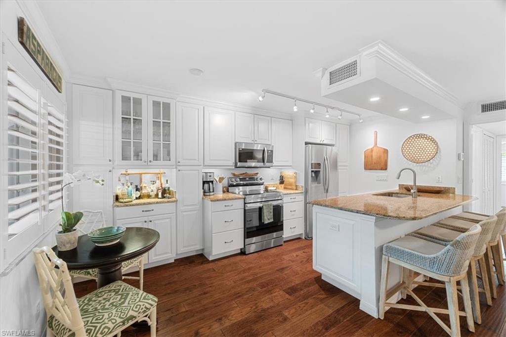 380 4th Avenue South, Unit 380 Naples, FL 34102 - Photo 4 of 19 a kitchen with granite countertop kitchen island stainless steel appliances a stove a table and chair