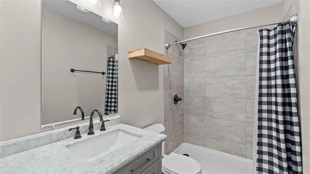 a bathroom with a granite countertop sink toilet and shower