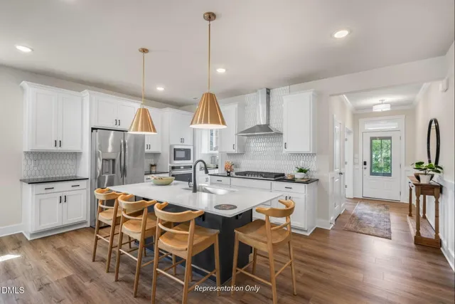 a kitchen with stainless steel appliances kitchen island granite countertop a refrigerator a stove a sink a dining table and chairs with wooden floor