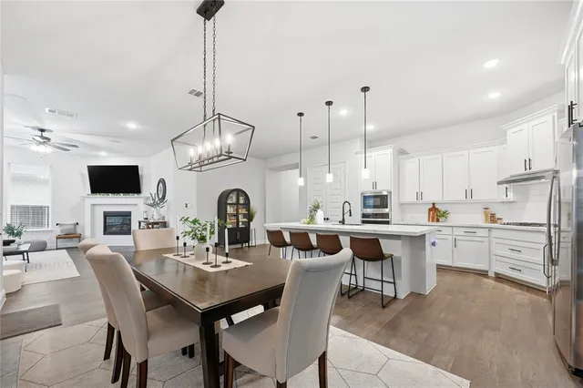 a dining room with stainless steel appliances kitchen island granite countertop a table chairs and a kitchen view