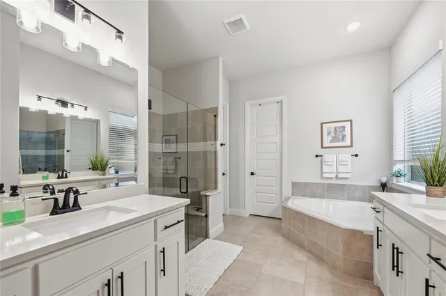 a large bathroom with a double vanity sink large mirror and a bath tub