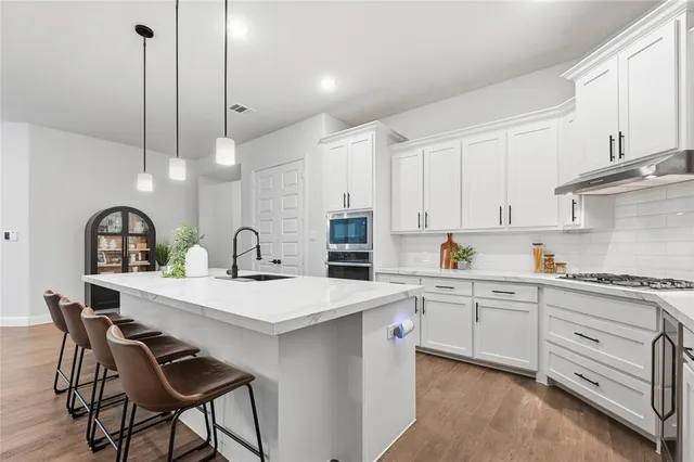a kitchen with stainless steel appliances a table chairs and white cabinets