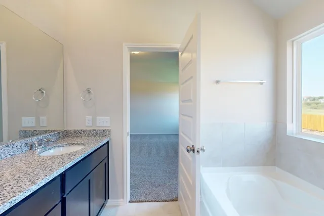 a bathroom with a granite countertop tub sink and mirror