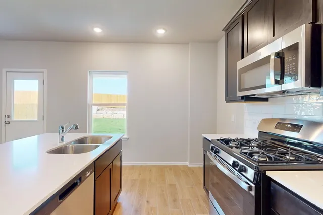 a kitchen that has a sink wooden cabinets and stainless steel appliances