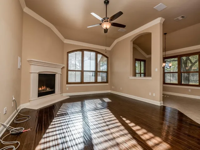 a view of an empty room with wooden floor fireplace and a window