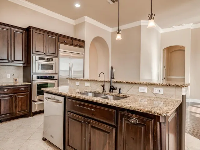 a kitchen with stainless steel appliances granite countertop a sink a stove and a wooden cabinets
