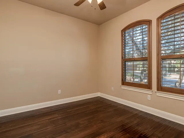 a view of an empty room with window and wooden floor