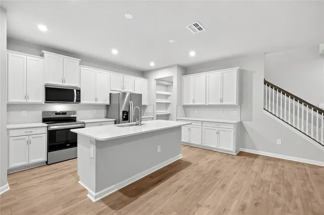 a kitchen with stainless steel appliances a stove a sink a microwave and cabinets