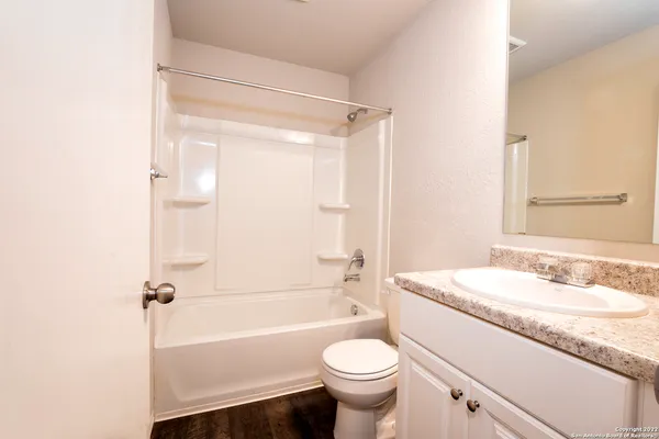 a bathroom with a granite countertop sink a toilet a mirror and shower