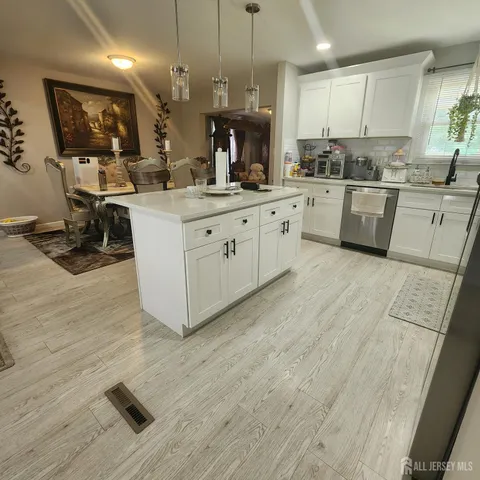 a large white kitchen with a stove a sink dishwasher and a refrigerator with wooden floor