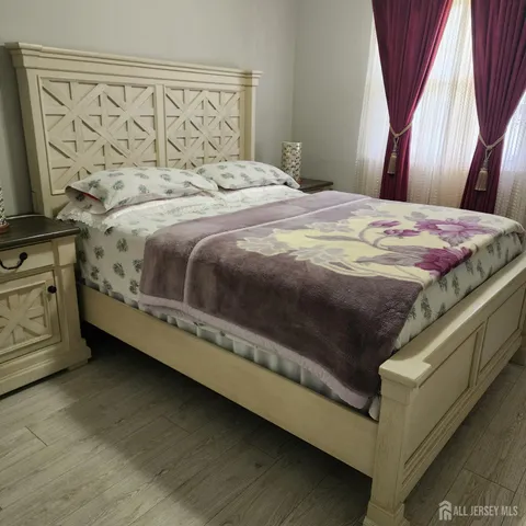a bed sitting in a bedroom next to a window with wooden floor