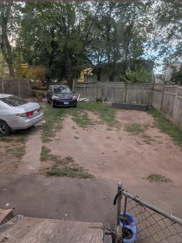 a view of a yard with car parked on the road