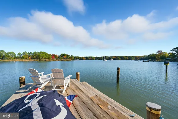 a view of a lake with a table and chairs next to an umbrella