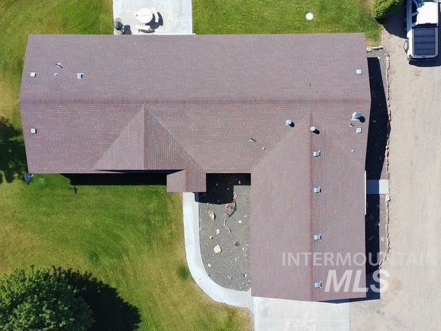 1095 County Road 70 Weiser, ID 83672 - Photo 2 of 44 Brown shingle roof with multiple roof vents, featuring a concrete patio, curved concrete pathway, and a gravel landscape area
