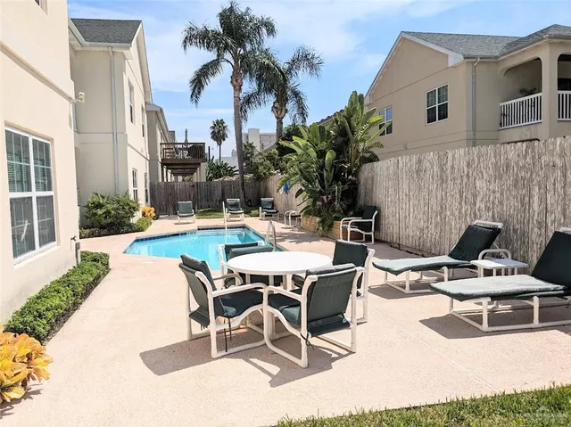a patio with a table and chairs and potted plants