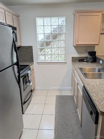 a kitchen with granite countertop a stove a sink and a refrigerator