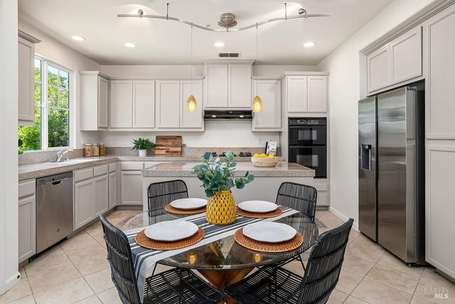 a kitchen with a refrigerator a stove a dining table and chairs