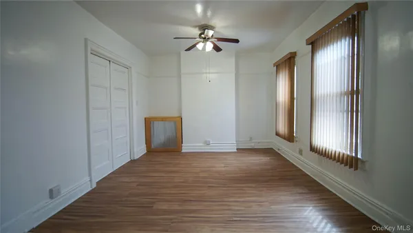 a view of an empty room with a window and wooden floor