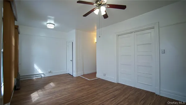 an empty room with wooden floor closet and windows
