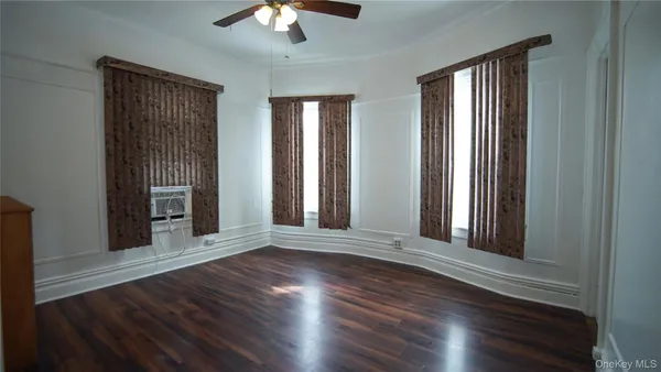 an empty room with wooden floor chandelier and windows