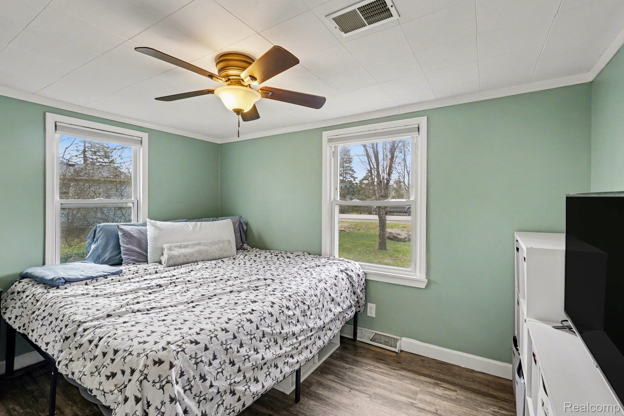 16485 Jennings Road Fenton, MI 48430 - Photo 20 of 27 Bedroom featuring wood finished floors, multiple windows, a ceiling fan, and crown molding
