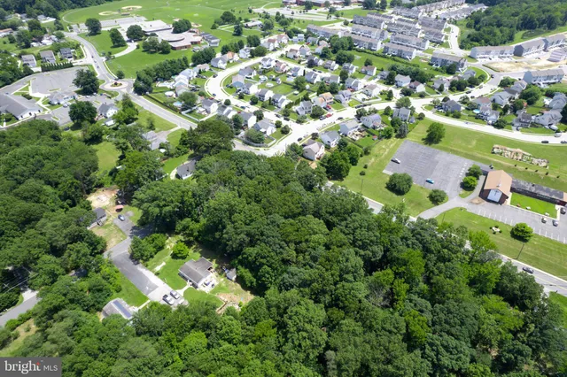 an aerial view of residential houses with outdoor space and trees all around