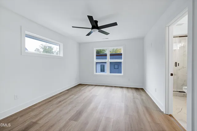 a view of empty room with wooden floor and fan