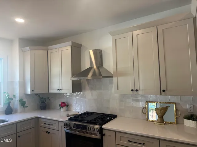 a kitchen with stainless steel appliances granite countertop a sink a stove and a white cabinets