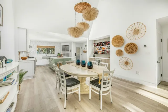 a dining room with wooden floor a chandelier a wooden table and chairs