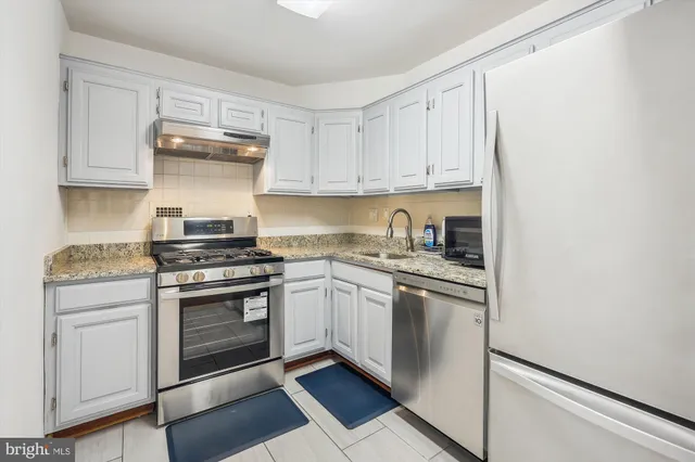 a kitchen with granite countertop white cabinets and white appliances