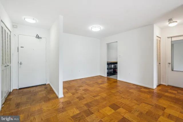 a view of an empty room with kitchen and a window