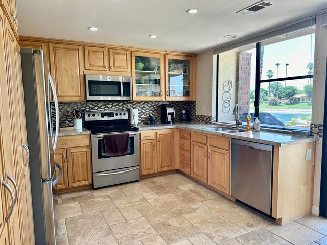 a kitchen with stainless steel appliances granite countertop a stove a sink and a refrigerator