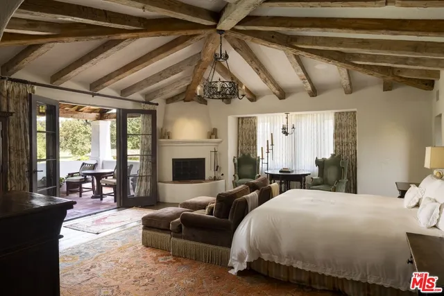 a spacious bedroom with a bed a couch and a chandelier